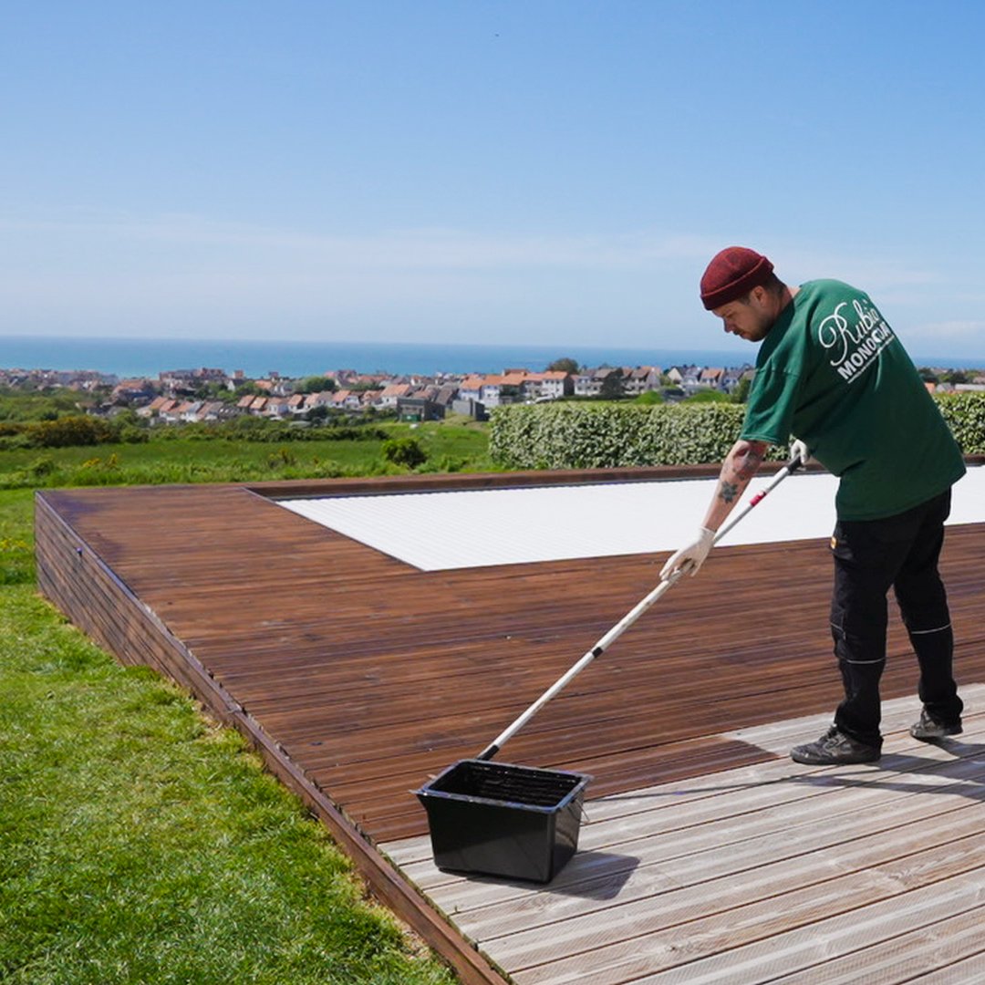 Man die DuroGrit op een houten terras aanbrengt