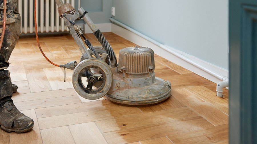 Olieën RIGA zet een houten vloer in de olie bij het renoveren van een houten vloer